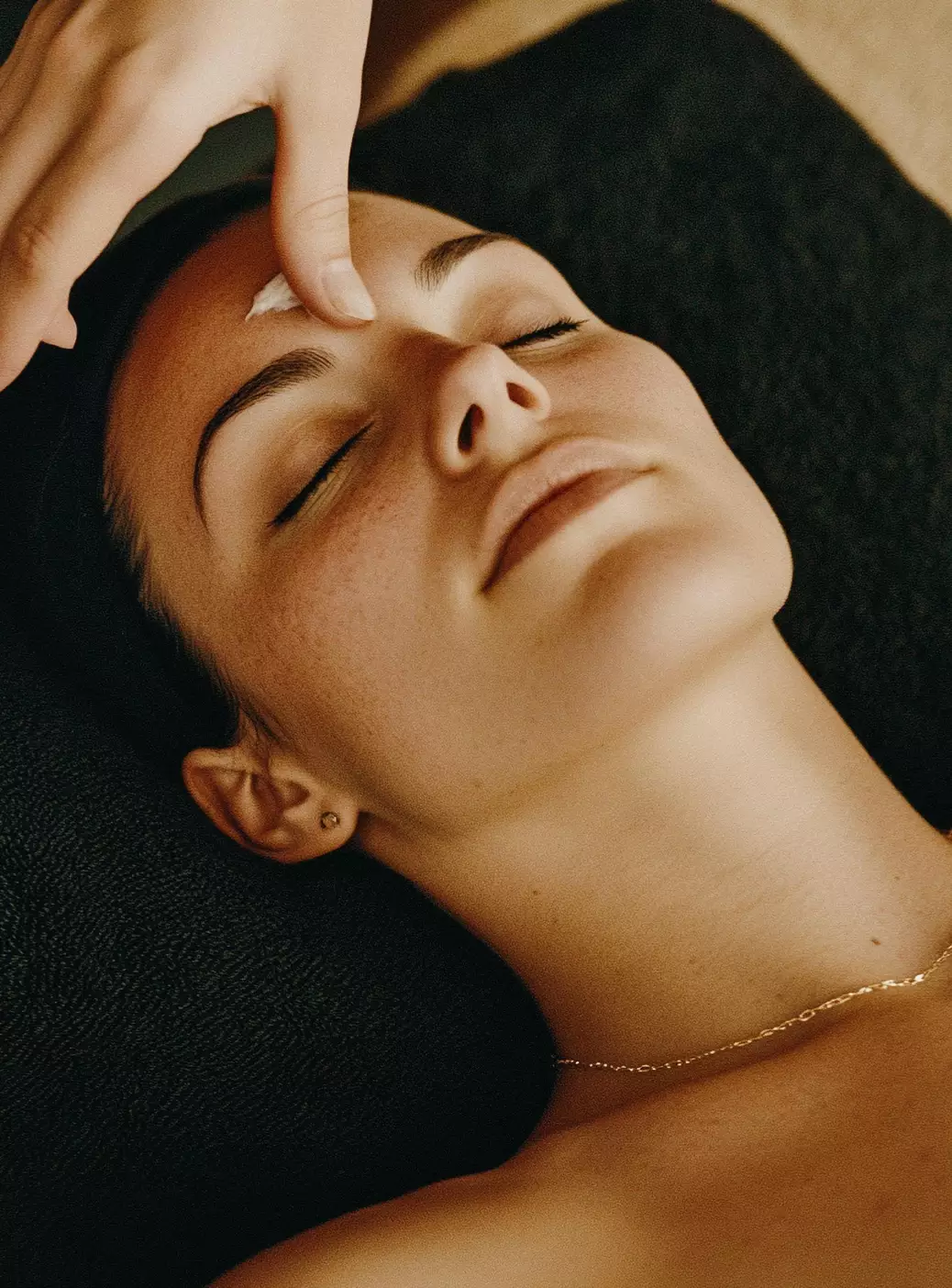 Close-up of a person receiving a relaxing forehead massage, symbolizing wellness and care for companions.