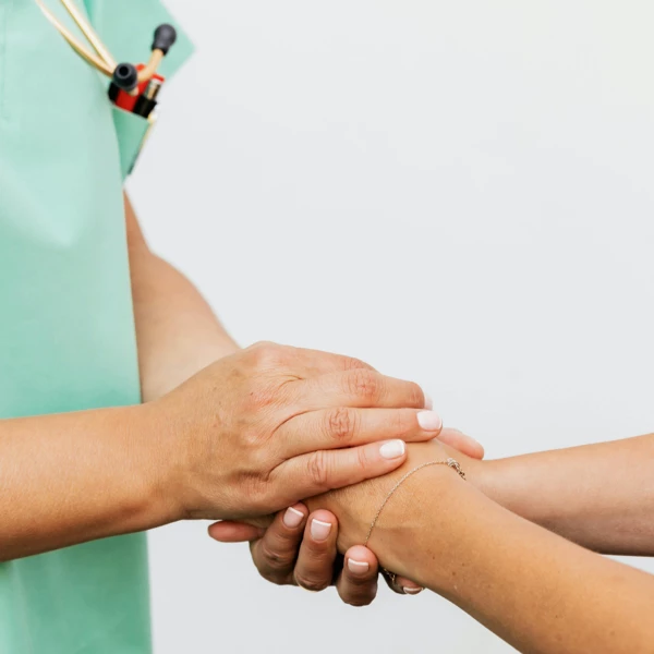 Nurse holding patient’s hand during daily visit to monitor healing and ensure comfort at Naghoi.